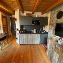 Una cocina compacta con armarios oscuros, encimera negra y una pared decorativa de piedra.