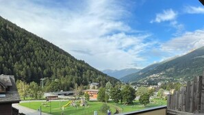 Vista de un valle con un parque infantil, una carretera y edificios a lo lejos.