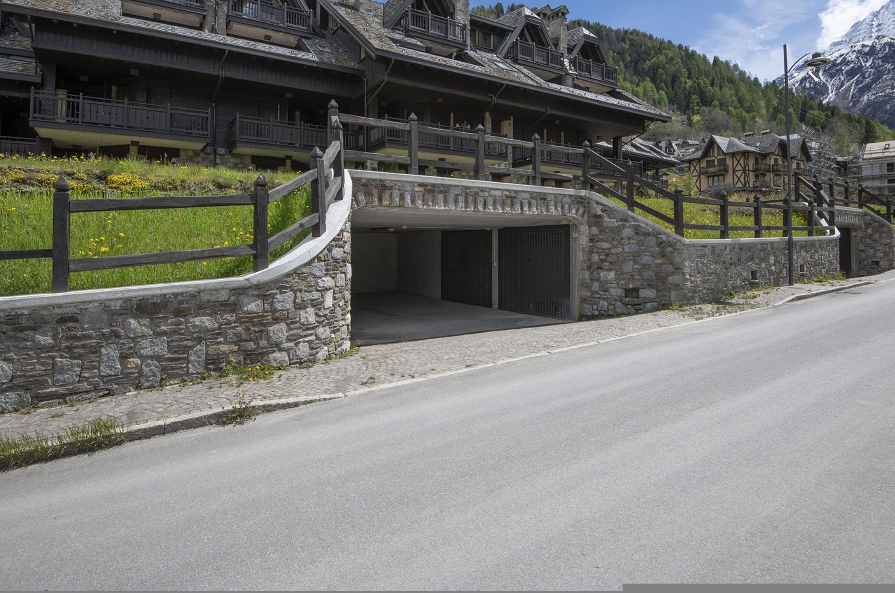 En traditionell byggnad i chaletstil med en fasad av sten, träbalkonger och en entré av sten.