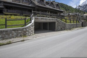 A traditional chalet-style building with a stone facade, wooden balconies, and a stone entrance.