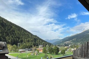 A view of a valley with a playground, a road, and buildings in the distance.