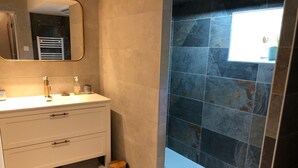A bathroom with a white vanity, a mirror, a towel rack, and a blue-tiled shower area.