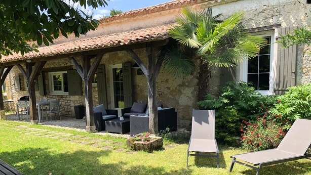 A covered outdoor seating area with wicker furniture and a lounge chair.