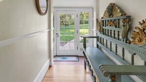 Un couloir avec un banc, une porte et un miroir.