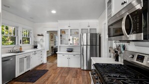 Une cuisine moderne dotée d’appareils électroménagers en acier inoxydable, de meubles blancs et d’un plancher en bois.