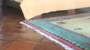 Una habitación con una cama, un tapete estampado y una araña.