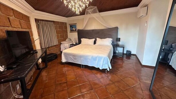 Un dormitorio con una cama grande, televisión y candelabro.