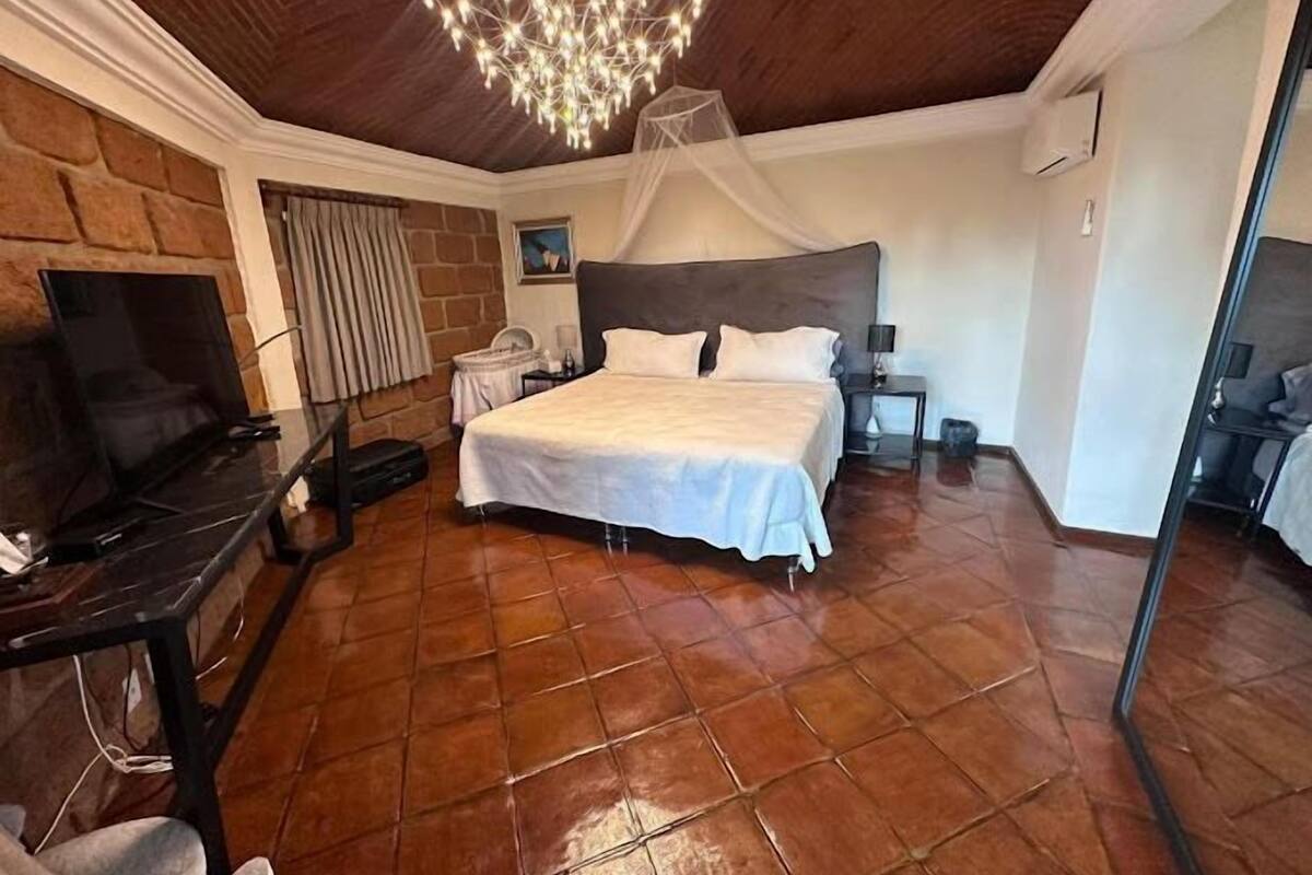 Un dormitorio con una cama grande, televisión y candelabro.