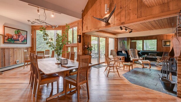 Een ruim houten interieur met een eethoek, zitplaatsen en een open haard.