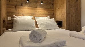 Una stanza con pannelli in legno, un letto, due cuscini, un asciugamano arrotolato e un comodino.