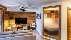 Un soggiorno moderno con parete in legno, una TV a schermo piatto, un divano e un'area pranzo con tavolo e sedie.
