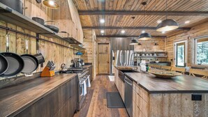 Een moderne keuken met houten wanden, roestvrijstalen apparatuur en hangende lampen.