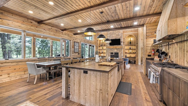 Een ruime keuken met houten wanden en een groot kookeiland, met een stenen open haard en moderne apparatuur.