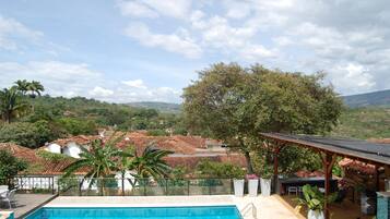 Piscina con vistas a casas escalonadas y un árbol grande.