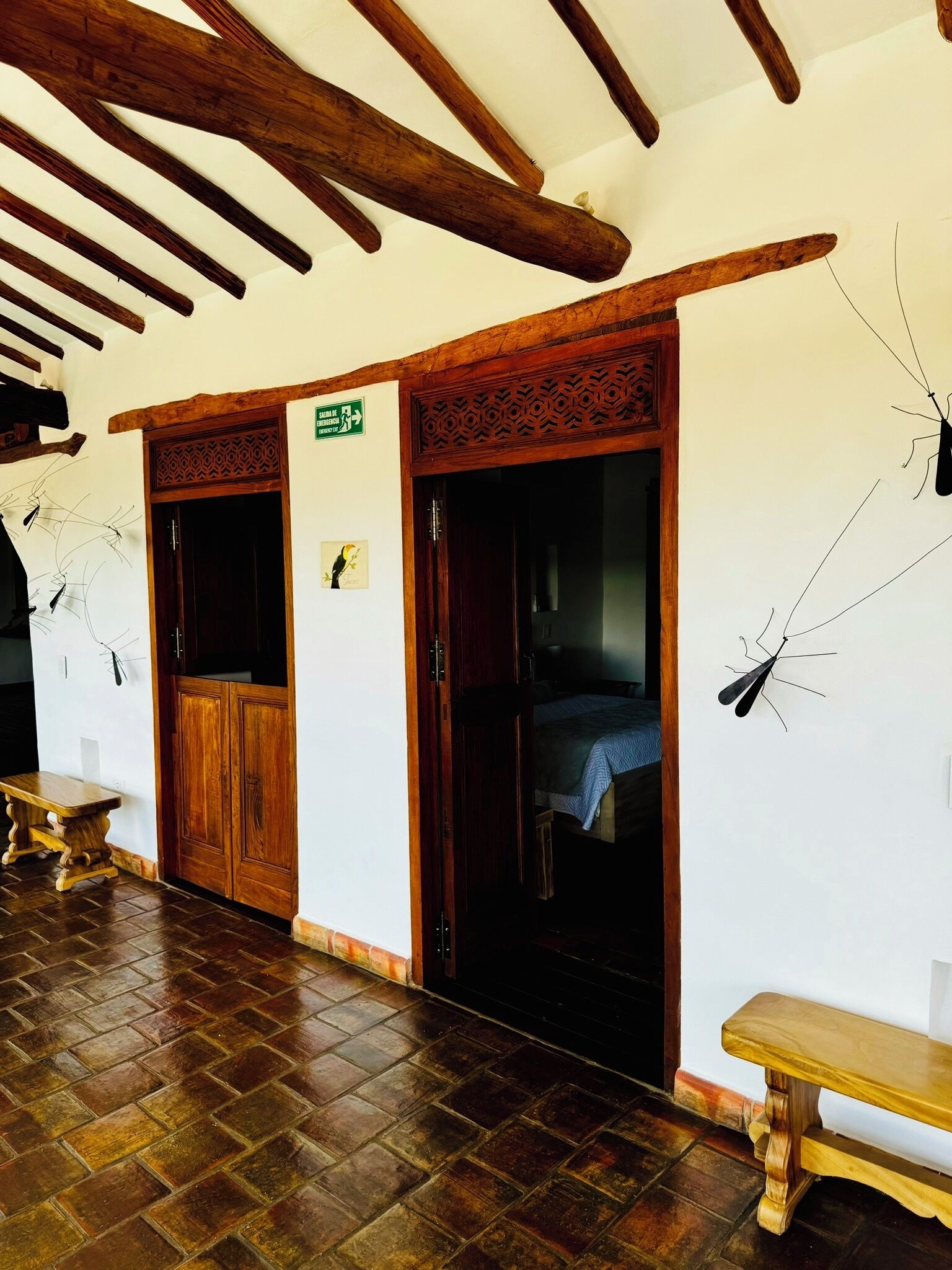 Un pasillo con puertas de madera, un banco y un cartel que indica una habitación.