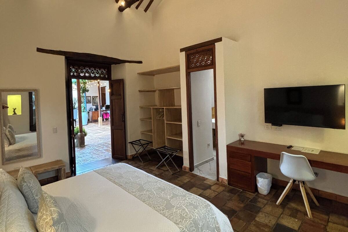 Une chambre avec un grand lit, un bureau, une télévision et une armoire.
