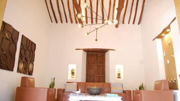 Un amplio salón con una lámpara moderna, sofás de cuero, una mesa de centro y decoración mural.