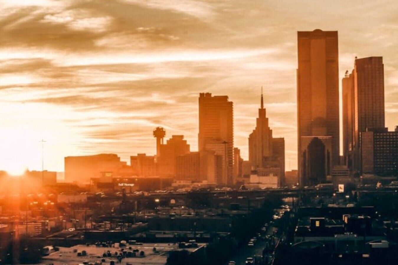 A city skyline with prominent high-rise buildings, including a tall skyscraper with a pointed top, and a mix of other structures.
