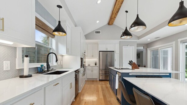 A modern kitchen with white cabinetry, a central island, and pendant lighting.