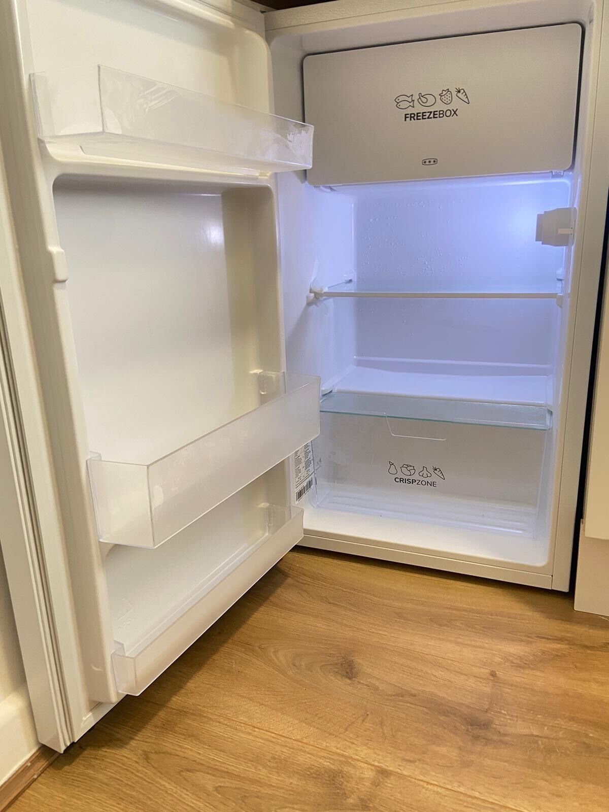 An open refrigerator with a freezer compartment on top and a crisper drawer at the bottom.