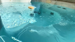Een bubbelbad met een houten zitplaats en opstijgende bubbels.