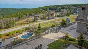A residential area with a swimming pool, outdoor seating, and a view of a forested hill. - Soaring Eagle  311 Ski In Out (Snowshoe)