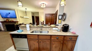 A kitchen with a built-in dishwasher, wooden cabinets, a granite countertop, and a backsplash. - Soaring Eagle  311 Ski In Out (Snowshoe)