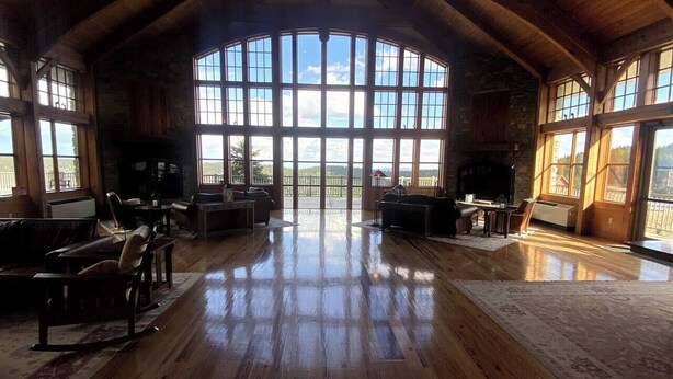 A spacious room with wooden floors and large windows, offering a view of the outdoors. - Soaring Eagle  311 Ski In Out (Snowshoe)