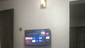 A room with a flat-screen TV mounted on the wall, a small refrigerator, and a door. - Lagos - 1bed - Sleeps 2 - Aircon - Free Parking (Lagos)