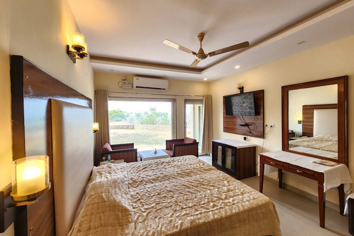 A hotel room with a bed, a desk, a chair, a TV, and a ceiling fan.