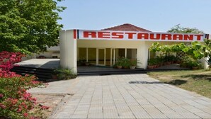 A restaurant with a clear entrance, a tiled walkway, and potted plants around. - Barbet Tourist Resort (Sohna)