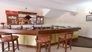 A bar area with a wooden counter, three bar stools, and a mirror above the counter. - Barbet Tourist Resort (Sohna)