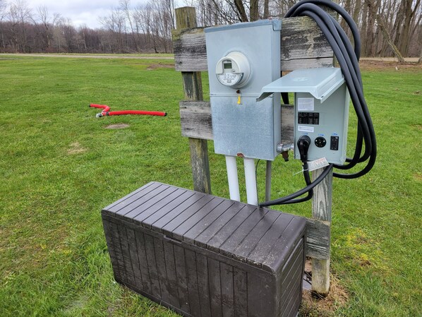 An outdoor electrical box with a digital display, connected to a wooden post and a metal box. - Pondside Campground 2 (Meadville)