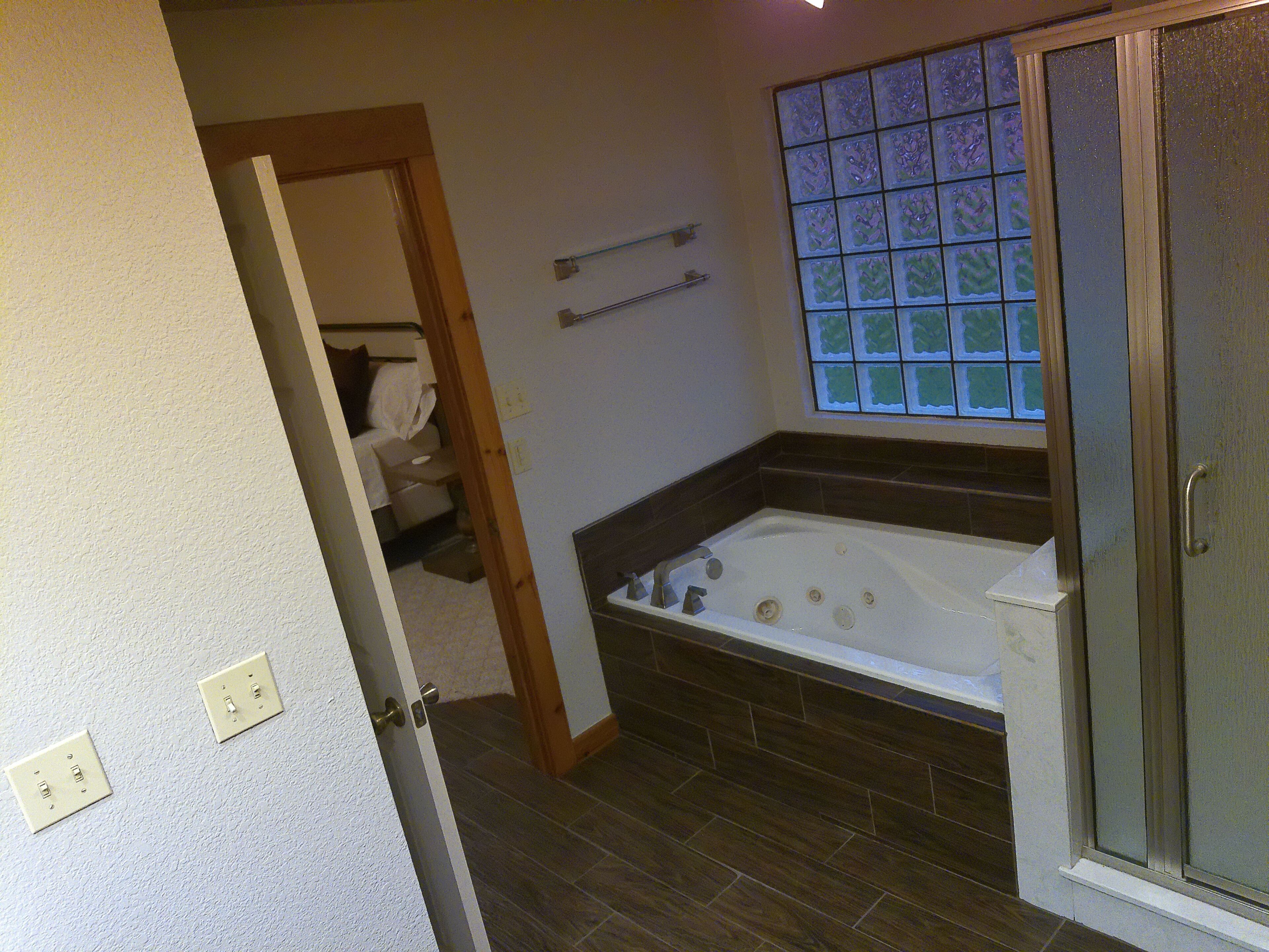 Une salle de bain équipée d’une baignoire, d’une douche et d’une fenêtre agrémentée d’un panneau de verre décoratif.