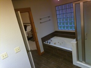 A bathroom with a bathtub, a shower, and a window with a decorative glass panel.