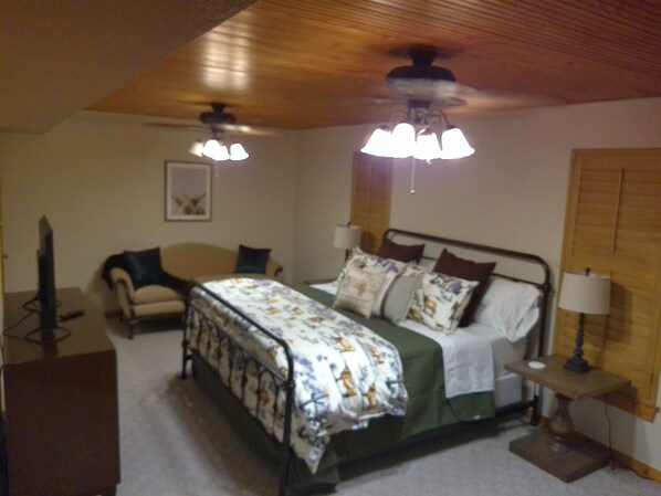 A bedroom with a bed, a chair, a desk, and a ceiling fan.