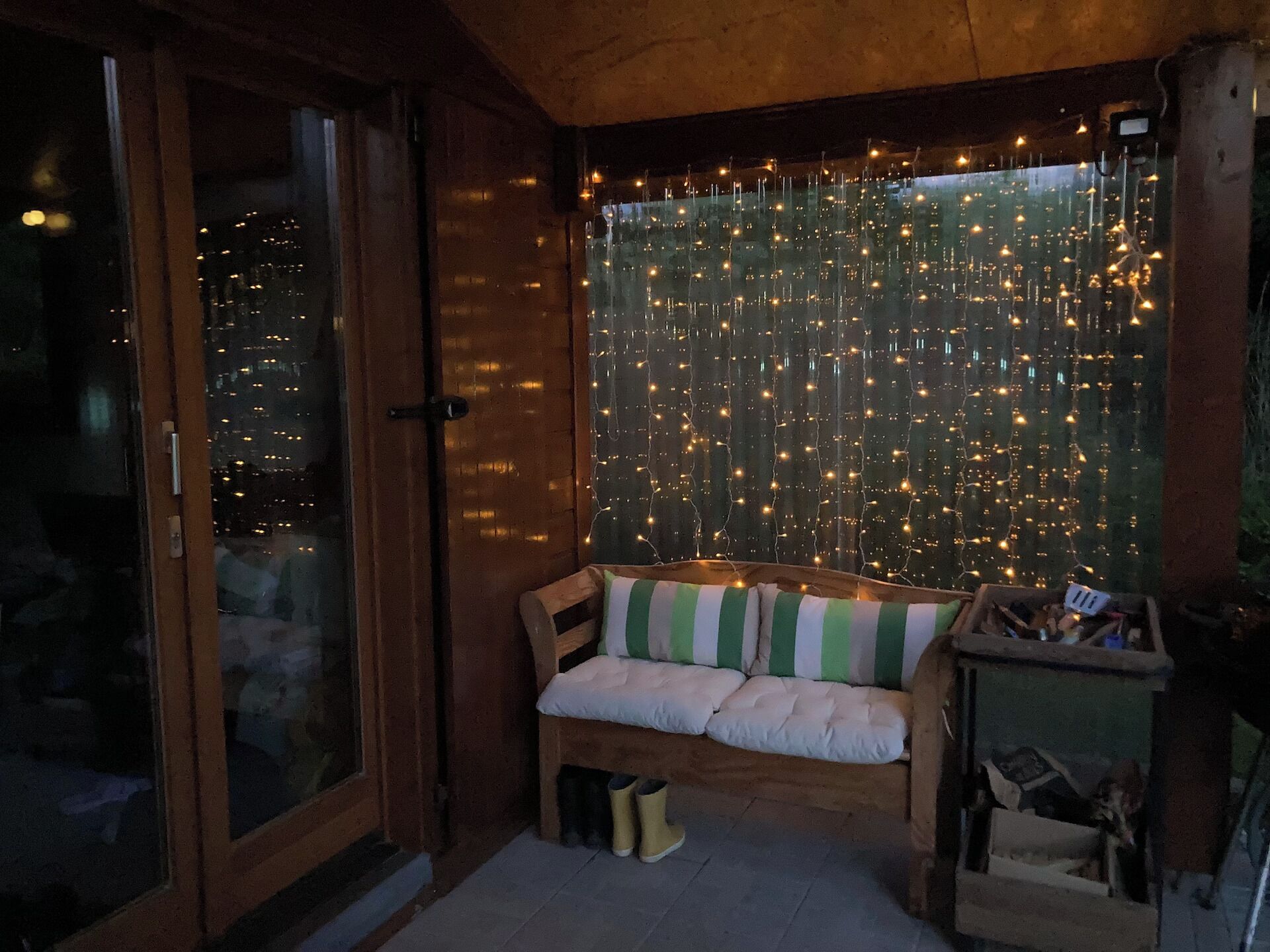Una habitación acogedora con un banco de madera, una mesita y una ventana decorada con luces de cuerda.