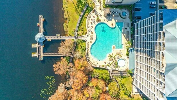 Vista aérea de un complejo turístico con una gran piscina, un muelle y un aparcamiento.