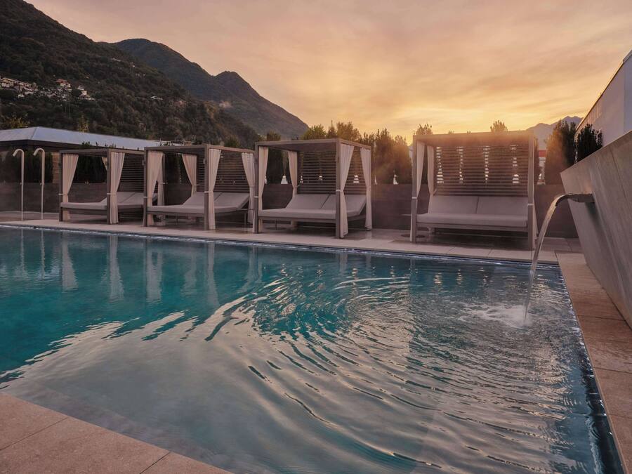 Una piscina con sillas de descanso y una fuente de agua.