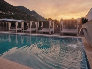 A swimming pool with lounge chairs and a water feature.