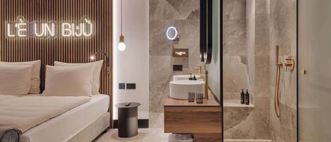 A modern bedroom with a bed, bedside table, and a neon sign.