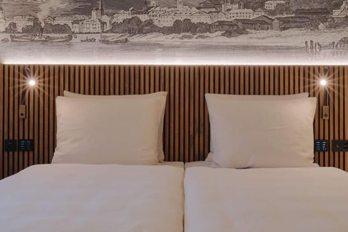 A double bed with a headboard featuring vertical wooden slats and a cityscape artwork above.