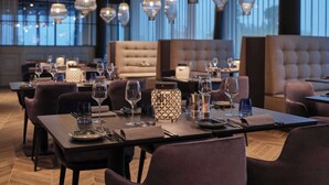 A modern restaurant with multiple tables set for dining, featuring elegant lighting fixtures and a cozy seating area. - Dorint Resort & Spa Locarno Riazzino (Locarno)