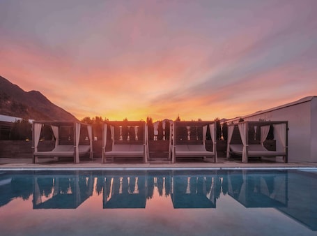 Una piscina al aire libre, sombrillas, sillones reclinables de piscina