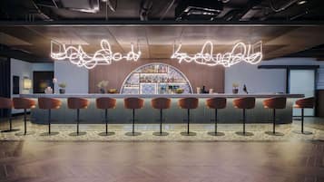 A bar area with a long counter, multiple stools, and a central display of bottles.