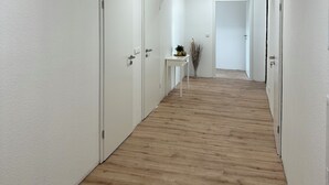 A hallway with white walls, wooden flooring, and white doors. - Zentrales Neues, Modernes Apartment. Schneller Zugang Mittels Code-schloss (Herne)