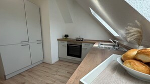 A modern kitchen with white cabinets, a wooden countertop, and a built-in oven. - Zentrales Neues, Modernes Apartment. Schneller Zugang Mittels Code-schloss (Herne)