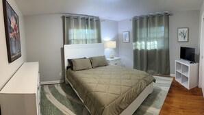 A bedroom with a bed, nightstands, a TV, and curtains. - Durham Vacation or Work Rental (Durham)