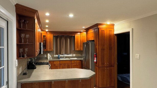 A modern kitchen with wooden cabinets, a stainless steel refrigerator, and a built-in island. - Durham Vacation or Work Rental (Durham)