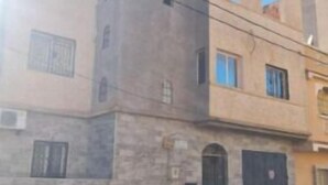 A multi-story building with a stone facade, a parked car, and a clear sky. - 2.simple, Sobre, Proche Mosquée et Belle Plage (Marsa Ben M'Hidi)